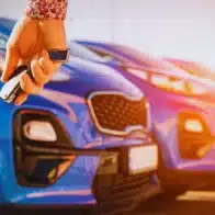 Hand holding car keys with blue cars behind. Rental Car Accidents